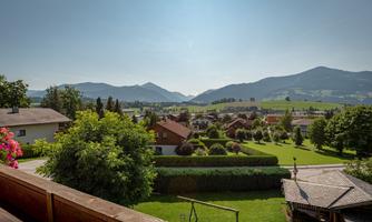 A picturesque landscape with green meadows and gentle hills. In the background, mountains and a clear sky are visible.