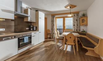 A modern kitchen with wooden accents and a cozy dining area. Large windows provide plenty of natural light.
