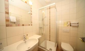 A modern bathroom with a shower, a sink, and a toilet. The walls are brightly tiled and the room feels clean and inviting.