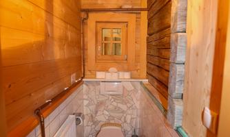 A rustic bathroom with wooden decor and tiles. It includes a toilet and a wall heater.