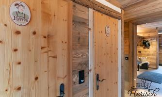 Two wooden doors in a rustic hallway, each with a plaque-like name. The room is cozy and features a natural wood appearance.