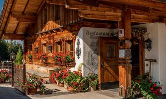 A traditional wooden house with flower pots and an inviting entrance. The restaurant has a rustic and cozy atmosphere.