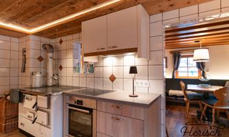 A modern kitchen with a wooden ceiling and light walls. The room is well-lit and offers a cozy dining area.