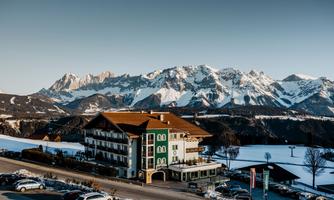 A beautiful hotel in the mountains with snow-covered peaks in the background. The tranquil landscape invites relaxation.