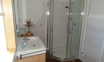 A modern bathroom with a shower and sink. The room is bright and well-maintained.