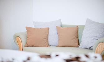 A cozy sofa with several pillows in neutral colors. The walls are bright and create an inviting atmosphere.