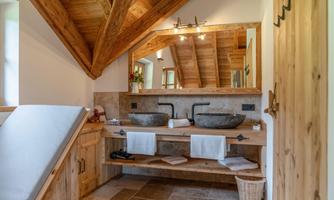 A modern bathroom with a wooden ceiling and two sinks. Bright, natural materials create an inviting atmosphere.