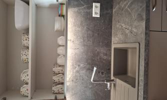 A modern kitchen with a gray countertop and a sink. The upper shelves are decorated with colorful dishware and cups.