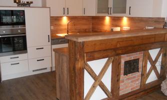 A modern kitchen with an elegant wooden countertop and white cabinets. The warm light accents create a cozy atmosphere.
