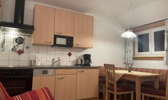A cozy kitchen with modern appliances and wooden cabinets. A dining table with chairs invites you to linger.