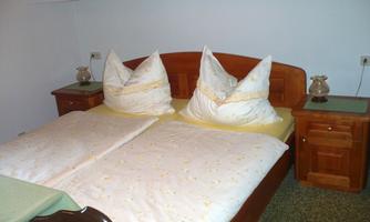 A cozy bedroom with a double bed that is equipped with two large pillows. Next to the bed are two nightstands with lamps.