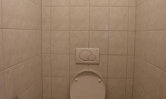 A simple bathroom with a toilet. The walls are tiled and the floor has a checkered pattern.