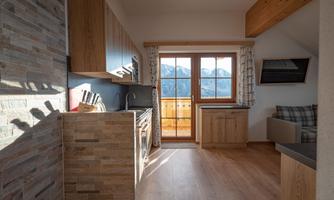 A modern kitchen with wooden cabinets and a large window that offers a view of the mountains. The space is bright and inviting.