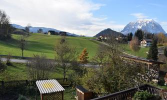 A beautiful landscape with green meadows and gentle hills. In the background, a majestic mountain rises.