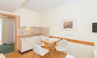 A bright kitchen with a table and chairs. The walls are painted in a soft yellow tone and there is a small wall art.