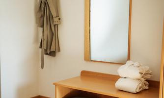 A cozy room with a wooden cabinet and a mirror. On the shelf are clean towels and a pillow.