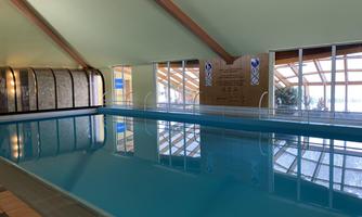 A bright, inviting swimming pool with clear water. Large windows provide a view of the surroundings and ensure plenty of daylight.