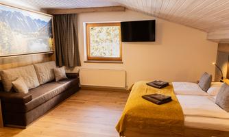 A cozy room with a double bed and a sofa.  
Large windows let in plenty of light and showcase a tranquil landscape.