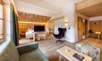 A modern room with wooden decor, a cozy seating area, and a television. Large windows let in plenty of light and create a relaxed atmosphere.
