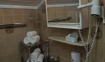 A small bathroom with a sink and a mirror. Towels are neatly stacked on a shelf.
