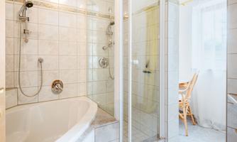 A modern bathroom with a bathtub and a separate shower. Bright tiles and spacious design give the room an inviting atmosphere.
