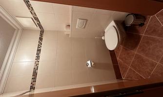 A small bathroom with a toilet and modern tiles. The walls are light and the furnishings are simple and functional.