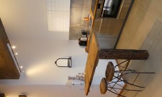 A modern kitchen with a wooden bar and two stools. Kitchen utensils and appliances are seen on the countertop.