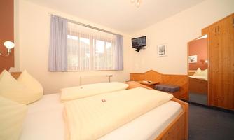 A cozy bedroom with two single beds and bright bedding. The room features a television and a large mirror.
