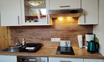 A modern kitchen with white cabinets and wood surfaces. The equipment includes a stove, a kettle, and a sink.