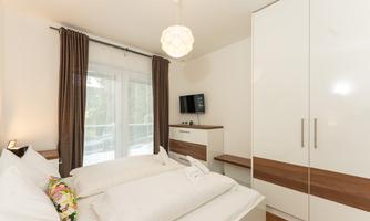 A modern bedroom with a double bed and a bright decor. A television and a large wardrobe are also available.