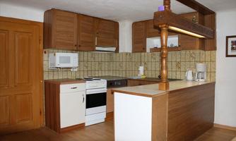 A modern kitchen with wood cabinets and a clear layout. The kitchen equipment includes a stove, a microwave, and a kettle.