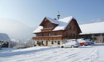 A charming wooden building in a snowy landscape. The surroundings are quiet and picturesque with mountains in the background.