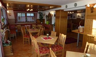 A cozy restaurant with wooden furniture and red checkered tablecloths. The room is well-lit and offers an inviting atmosphere.
