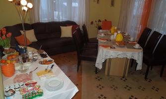 A cozy dining area with a beautifully set table and a couch. Various groceries and fresh fruit are arranged on the table.