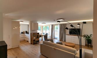 A modern living room with a bright color scheme. There is a cozy couch, a television, and a dining table.