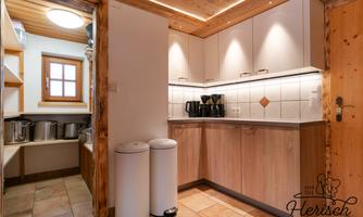 A modern kitchen with light wood and tile surfaces. It is equipped with kitchen appliances and offers plenty of storage space.