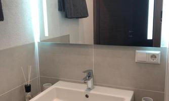 A modern bathroom with an elegant sink and a large mirror. The lighting is cozy and there are towels as well as decorative elements.