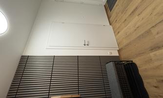 A modern hallway with a straight wall and minimalist accents. On the left side, there is a bench and mats are lying on the floor.