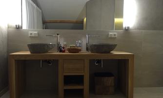 A modern bathroom with a wooden vanity and two decorative sinks. The cozy atmosphere is emphasized by soft lighting and stylish elements.