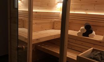A stylish sauna interior made of wood with gentle lighting. The benches are placed sufficiently for relaxation.