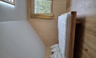 A cozy bedroom with a wooden bed and colorful curtains. The room has a warm, inviting atmosphere and a window with a view of nature.