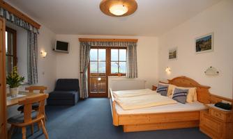 A cozy room with a double bed and a small dining area. Large windows provide plenty of daylight and a beautiful view.