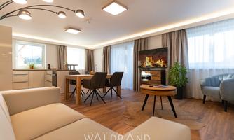 A bright and modern living kitchen with a cozy dining area. The fireplace and the windows create an inviting atmosphere.