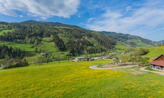 A beautiful landscape with green meadows and mountains in the background. The sky is blue with a few clouds.