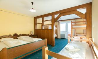 A simple room with two single beds and a bunk bed. The walls are painted yellow, and there is a window with a view outside.