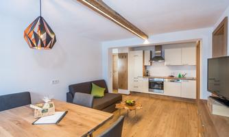 A modern apartment with an open living and kitchen area. The space is bright and inviting, with wooden floors and stylish lighting.
