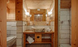 A modern bathroom made of wood and stone. There is a stylish vanity with a sink and towels, as well as a shower.