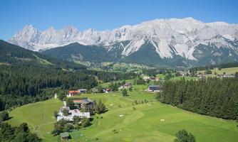A picturesque mountain landscape with majestic peaks and lush green meadows. Small houses are nestled in the idyllic surroundings.
