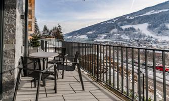 A balcony with modern furniture and a view of snow-covered mountains. The scene is calm and inviting.