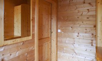 A room with wooden-paneled walls and a door. There is a large mirror on the wall.